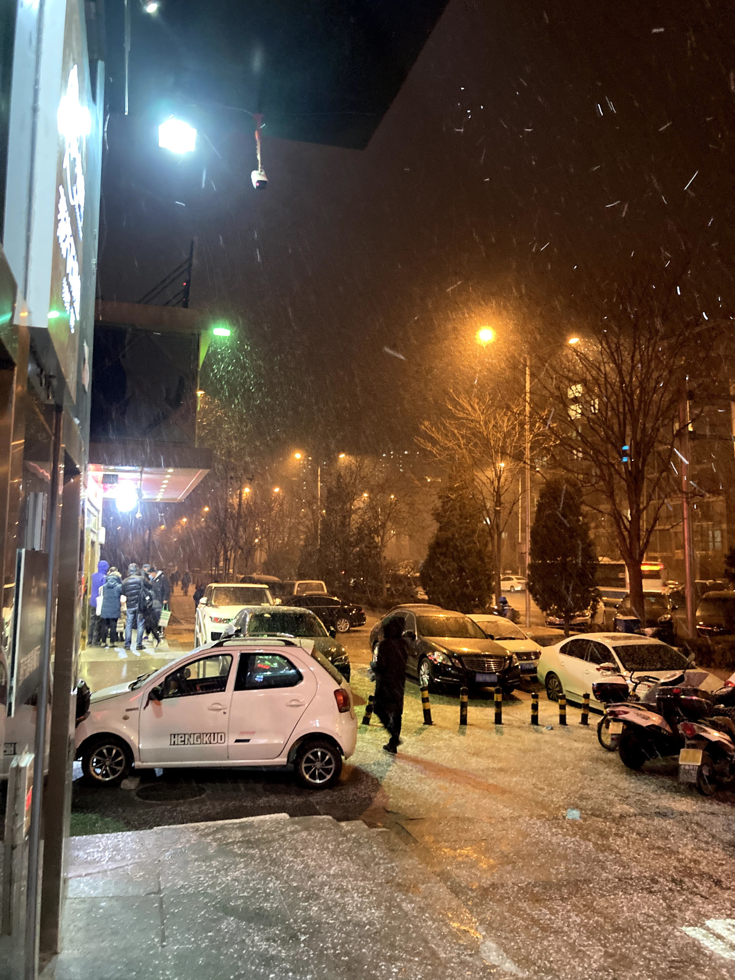 一张拍摄于下雪天的街景，车牌经过模糊处理
